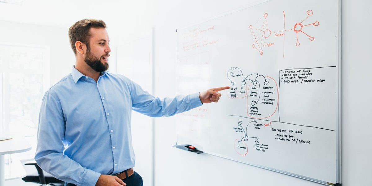 Man at white board performing IT consultation