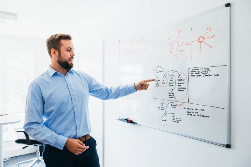 Man at white board performing IT consultation